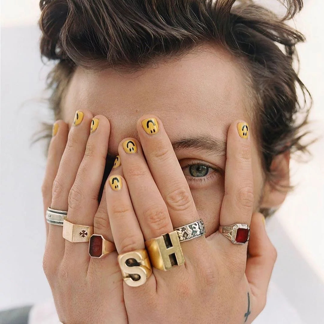 Harry Styles wearing mens nail art smileys on his fingers gloss effect.